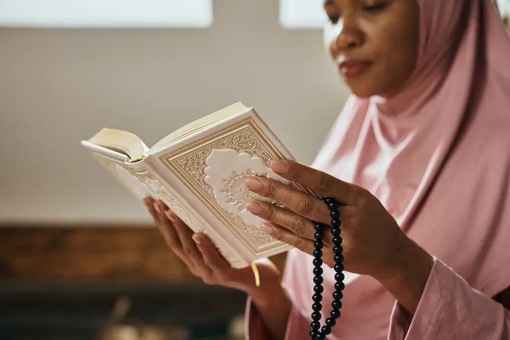 Muslim woman wearing hijab reading quran