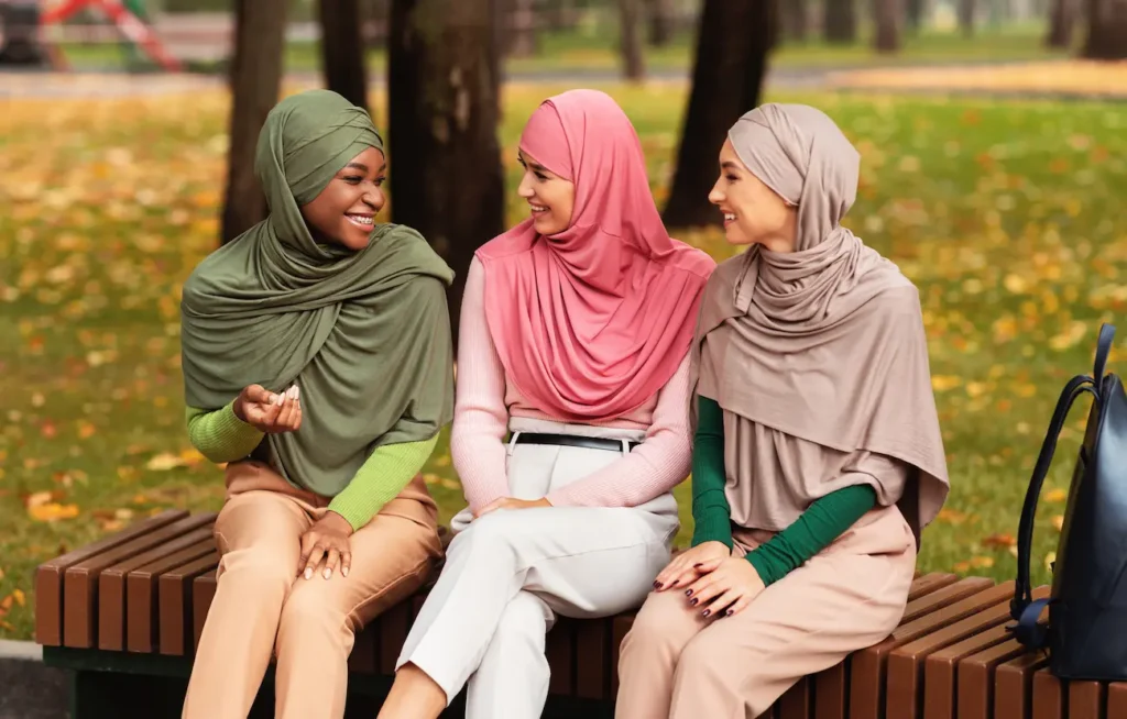 3 woman smiling seating on parc wearing tudung hijab